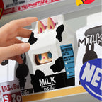 Toy figure in a milk box packaging with a hand interacting with it, displayed on a shelf.